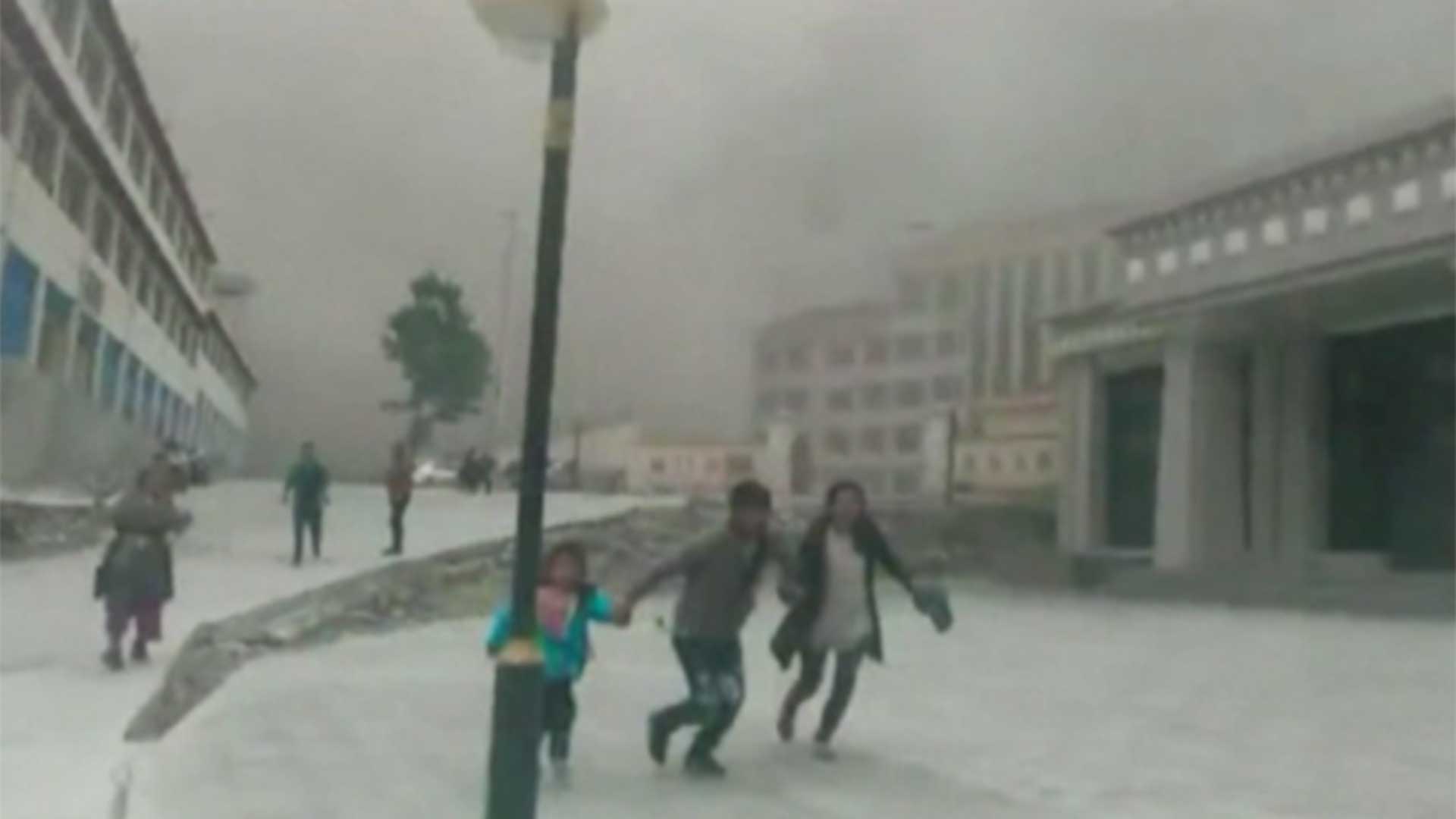 Residents grab one another and run for cover as dust fills the small town.