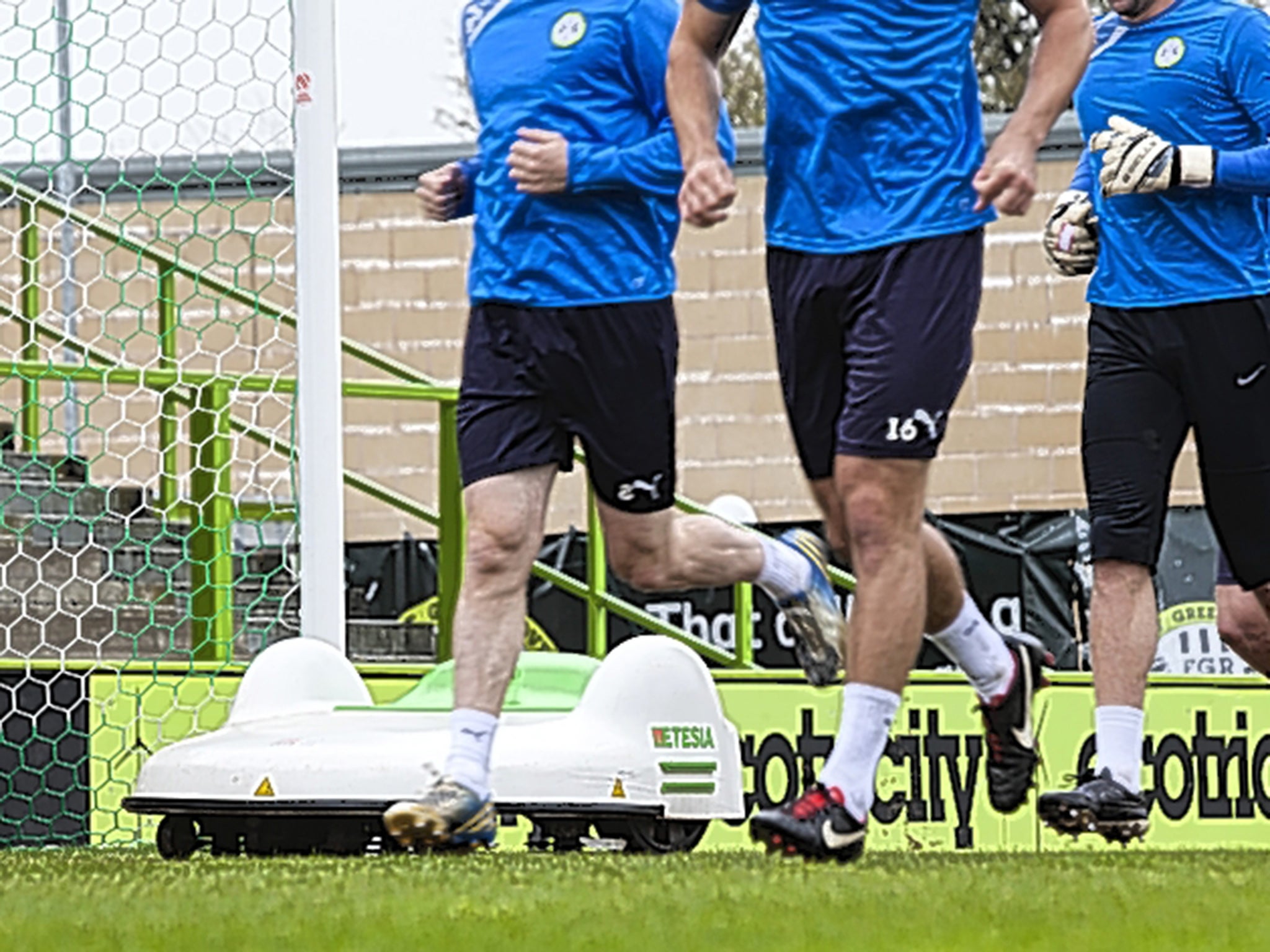 Players train alongside an automatic grass-cutting machin