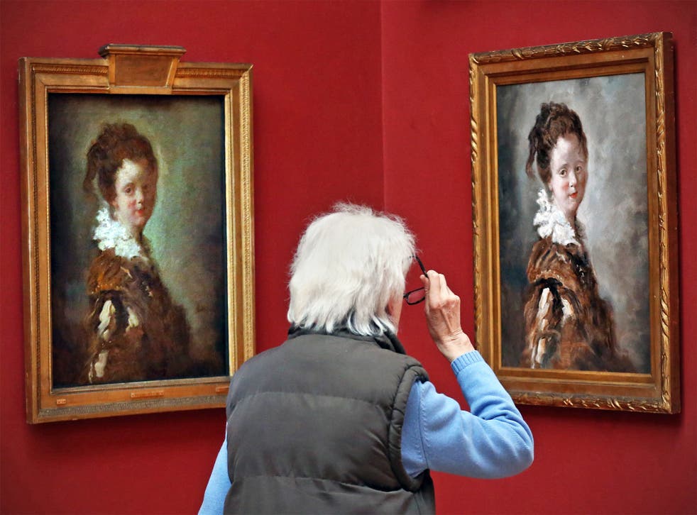 A visitor takes a close look at Jean-Honore Fragonard's ‘Young Woman’ and its replica (on right)