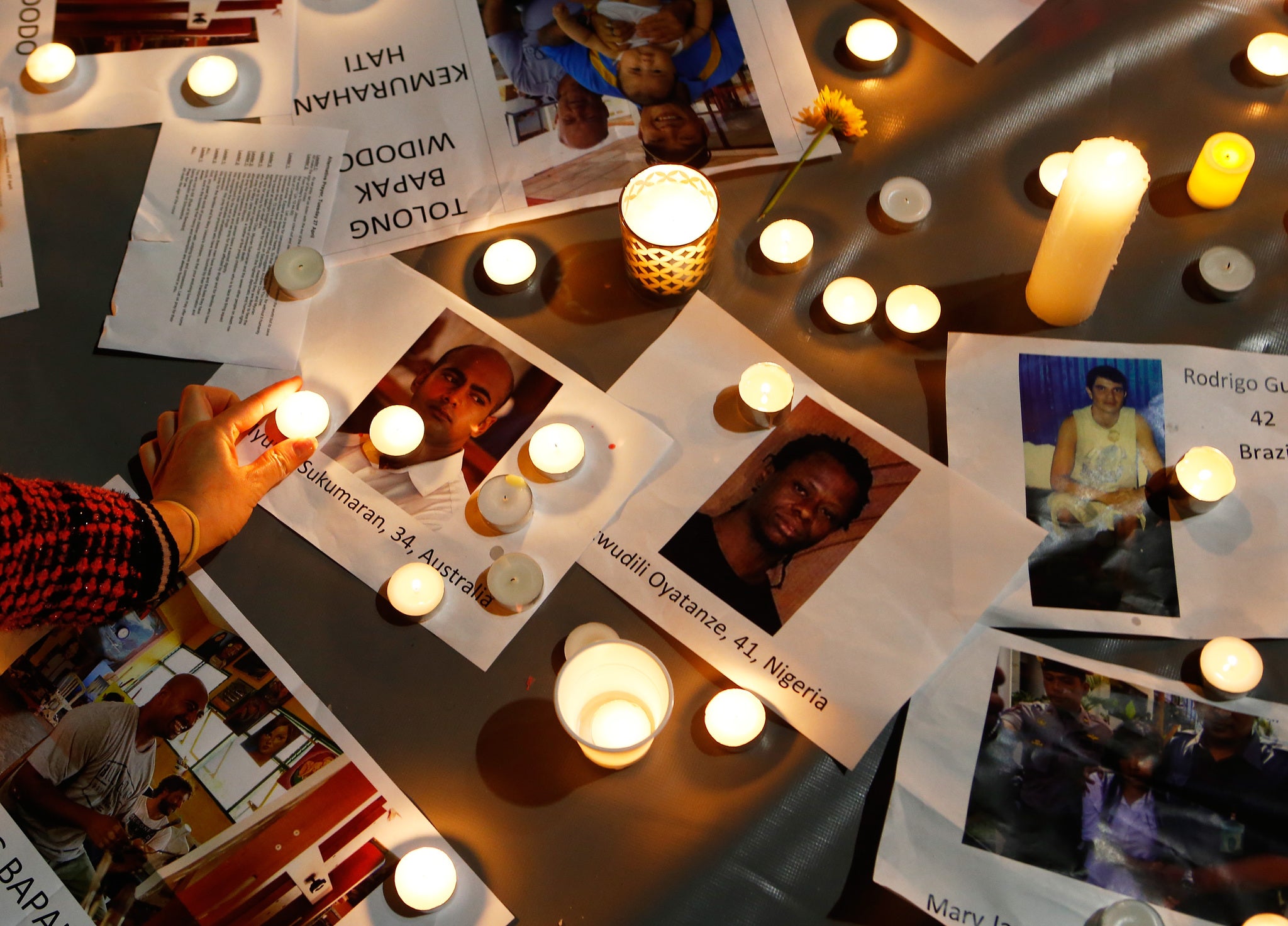 A woman places a candle on top of pictures of the prisoners to be executed in Indonesia, during a vigil at Martin Place in Sydney, Australia