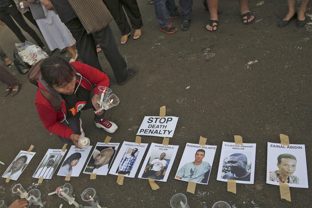 An activist holds candles near portraits of the 'Bali Nine' in Jakarta, Indonesia