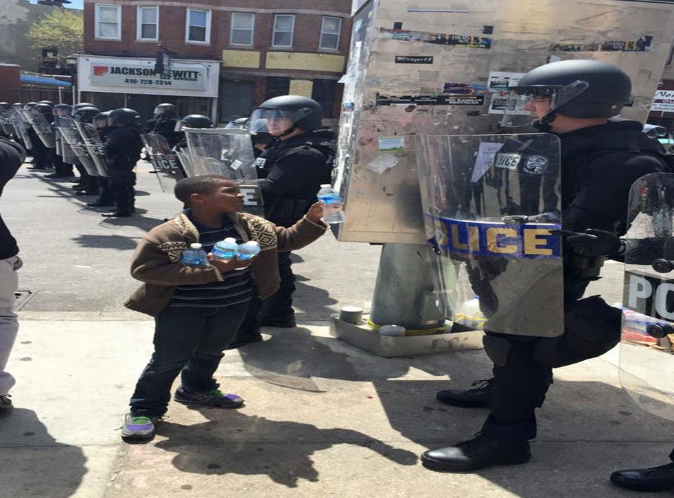 A young boy hands out water to police in Baltimore (Facebook: Bishop M Cromartie)