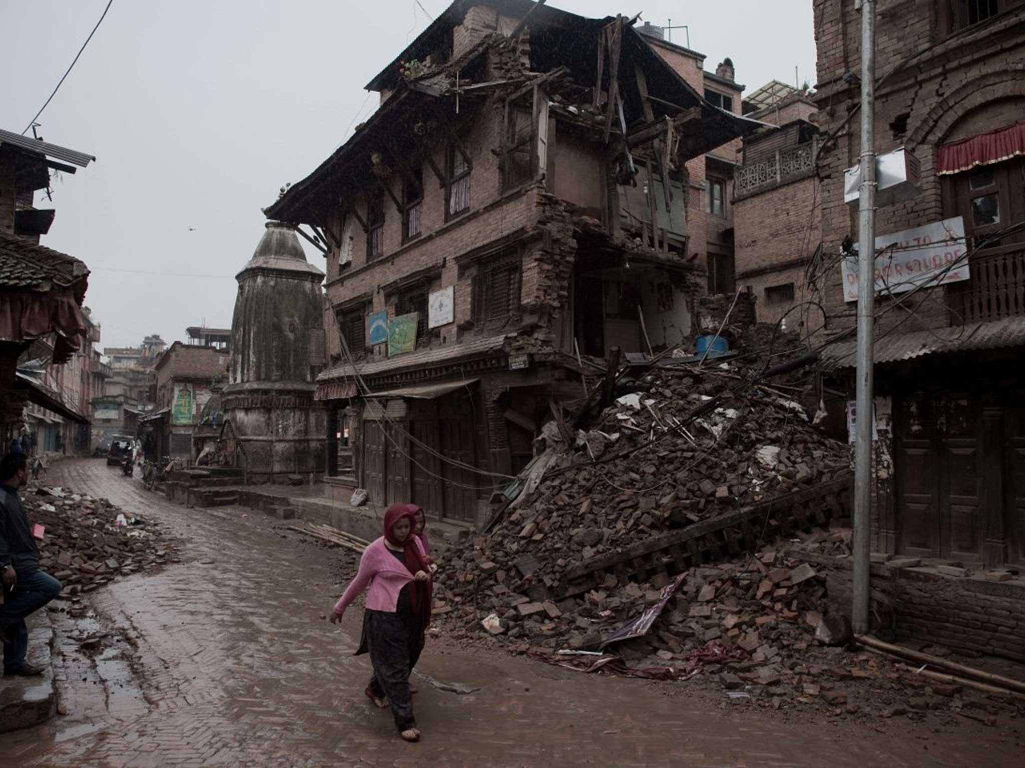 A Nepalese woman walks past the ruins of a home in Kathmandu