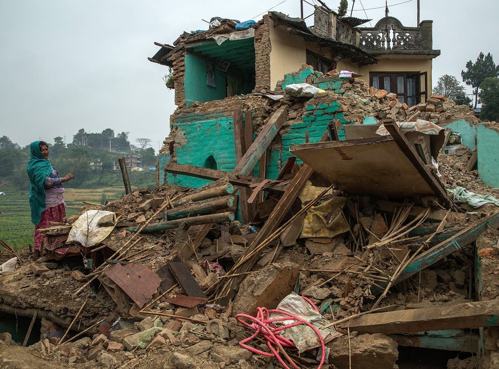 A woman stands on top of her collapsed home in Bungamati, Nepal, a destination formerly described as ‘a classic medieval village… one of the prettiest in the valley’