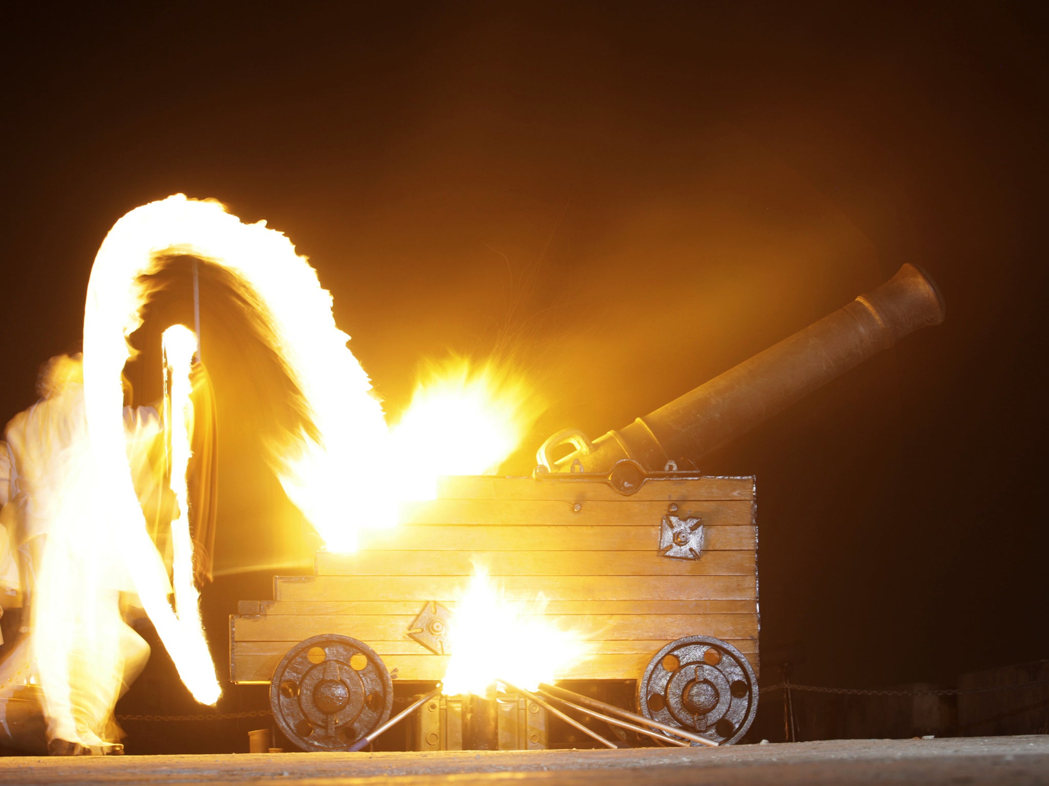 An army recruit dressed in an 18th century costume lights the fuse to fire a blank from a cannon during a ceremony known as "The Canonazo" in Havana. The ceremony is carried out every night at 9pm and was originally used to signal to the people that the g