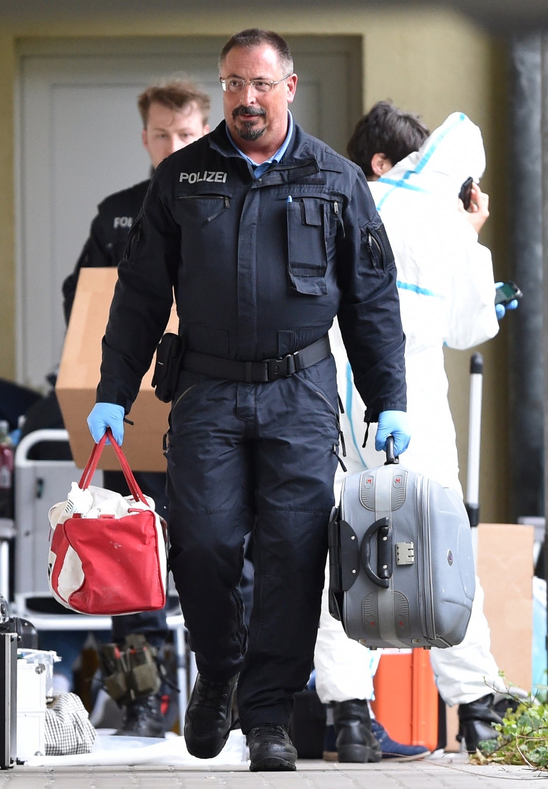 Police explosives experts carry evidence from an apartment complex in Oberursel, near Frankfurt, where the couple lived