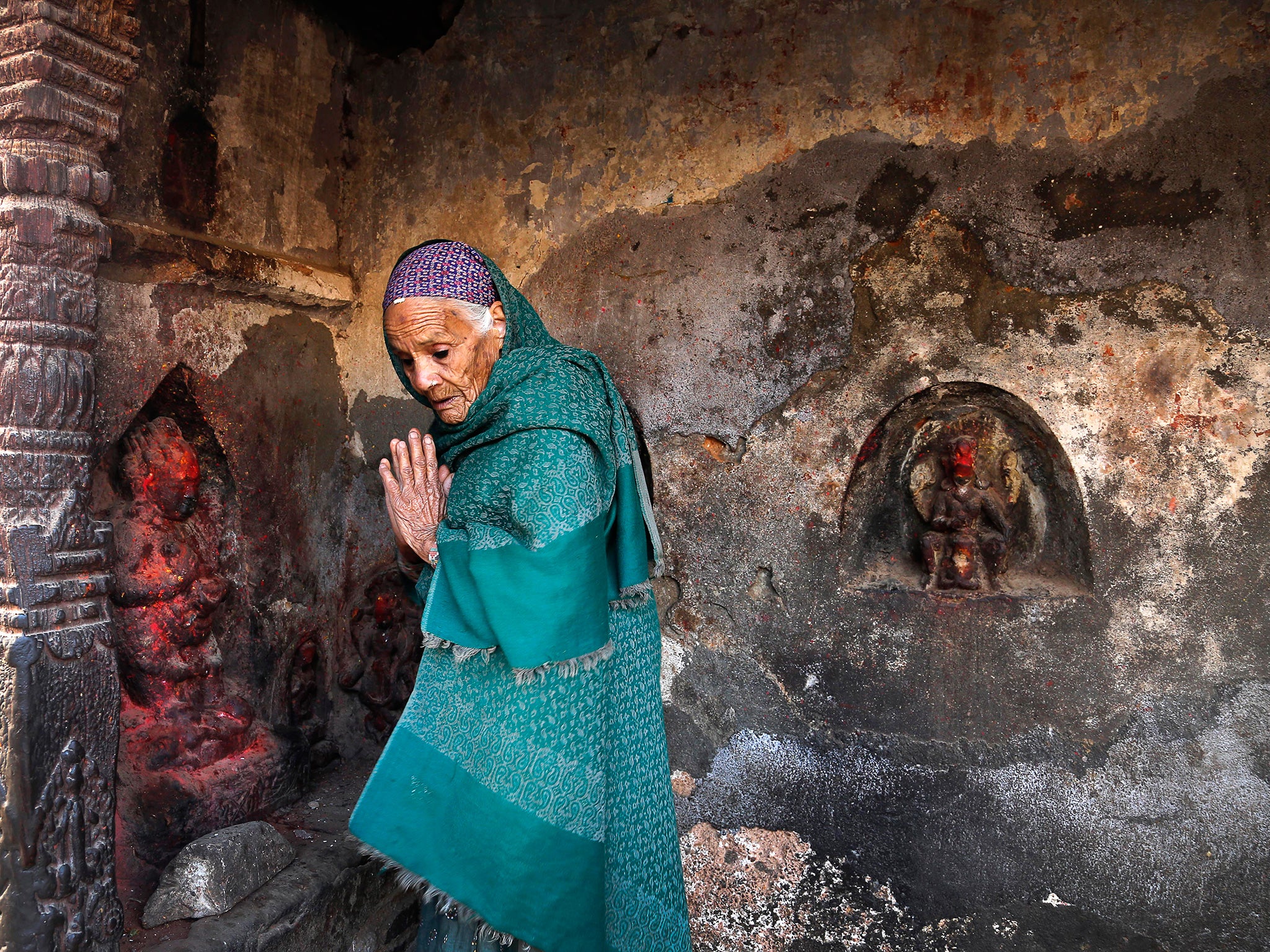 An elderly woman prays at a temple in Kathmandu damaged by the earthquake