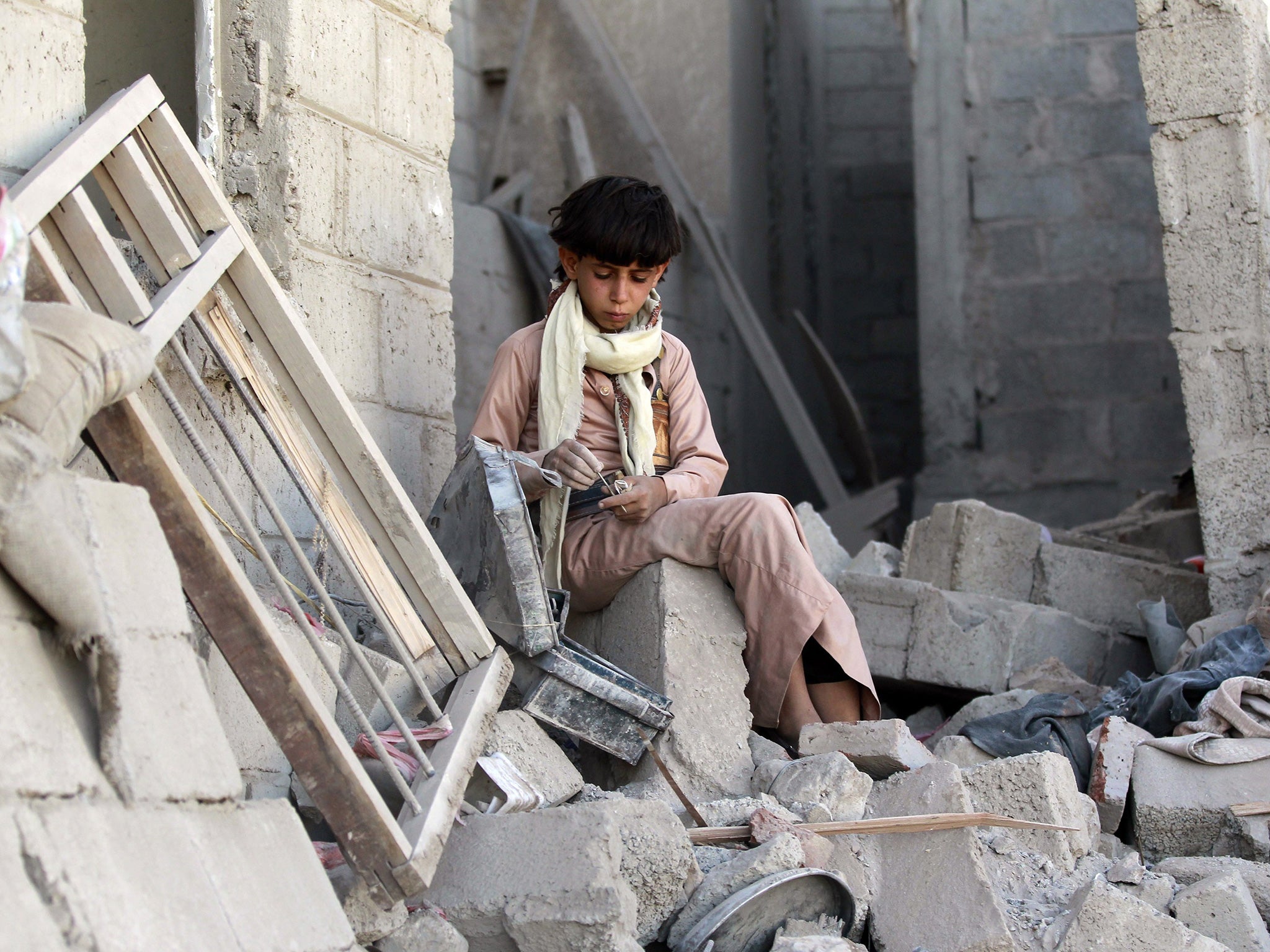 A Yemeni boys sits on the rubble of houses destroyed by an overnight Saudi-led air strike on a residential area in Yemen’s capital, Sana