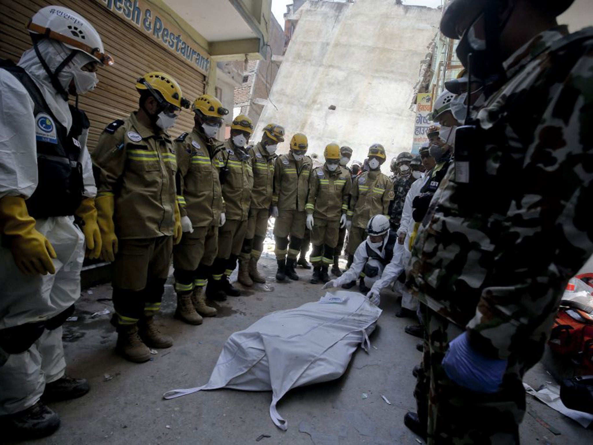 Teams of Korean NGO 'Human in Love' and Oman's national search and rescue team pay their respects to the body of a victim