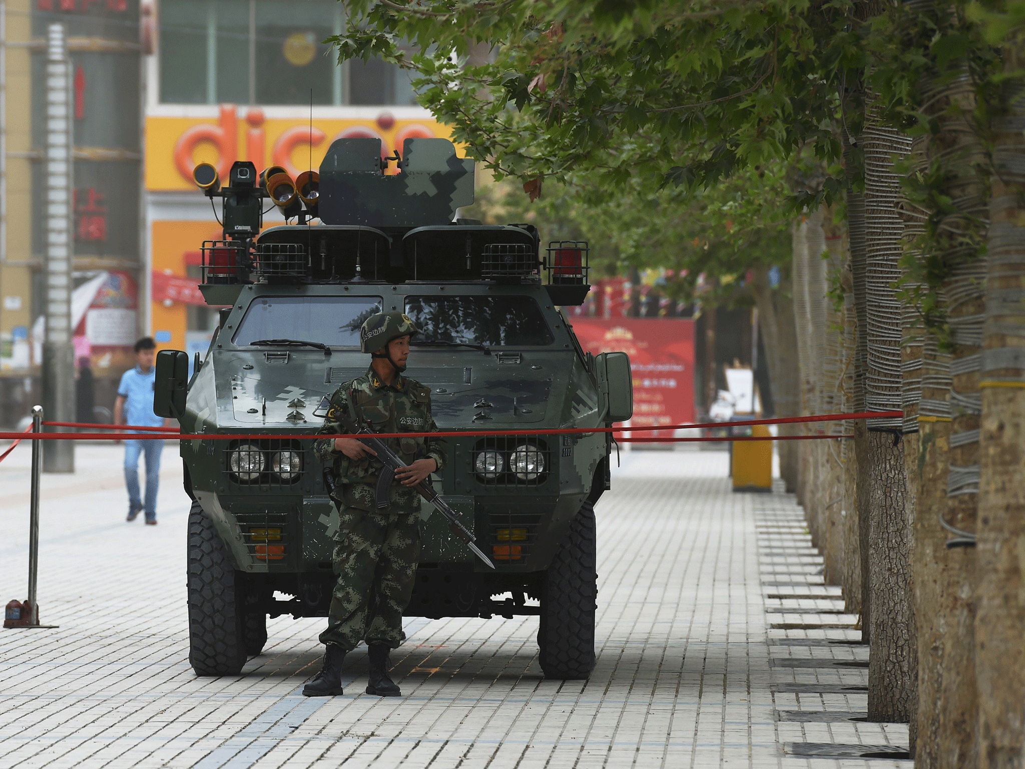 A paramilitary policeman stands guard in front of an armoured vehicle at the central square in Hotan
