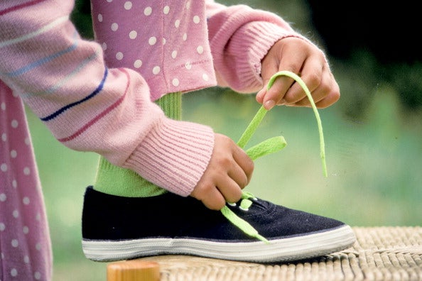 A girl masters tying her shoelaces