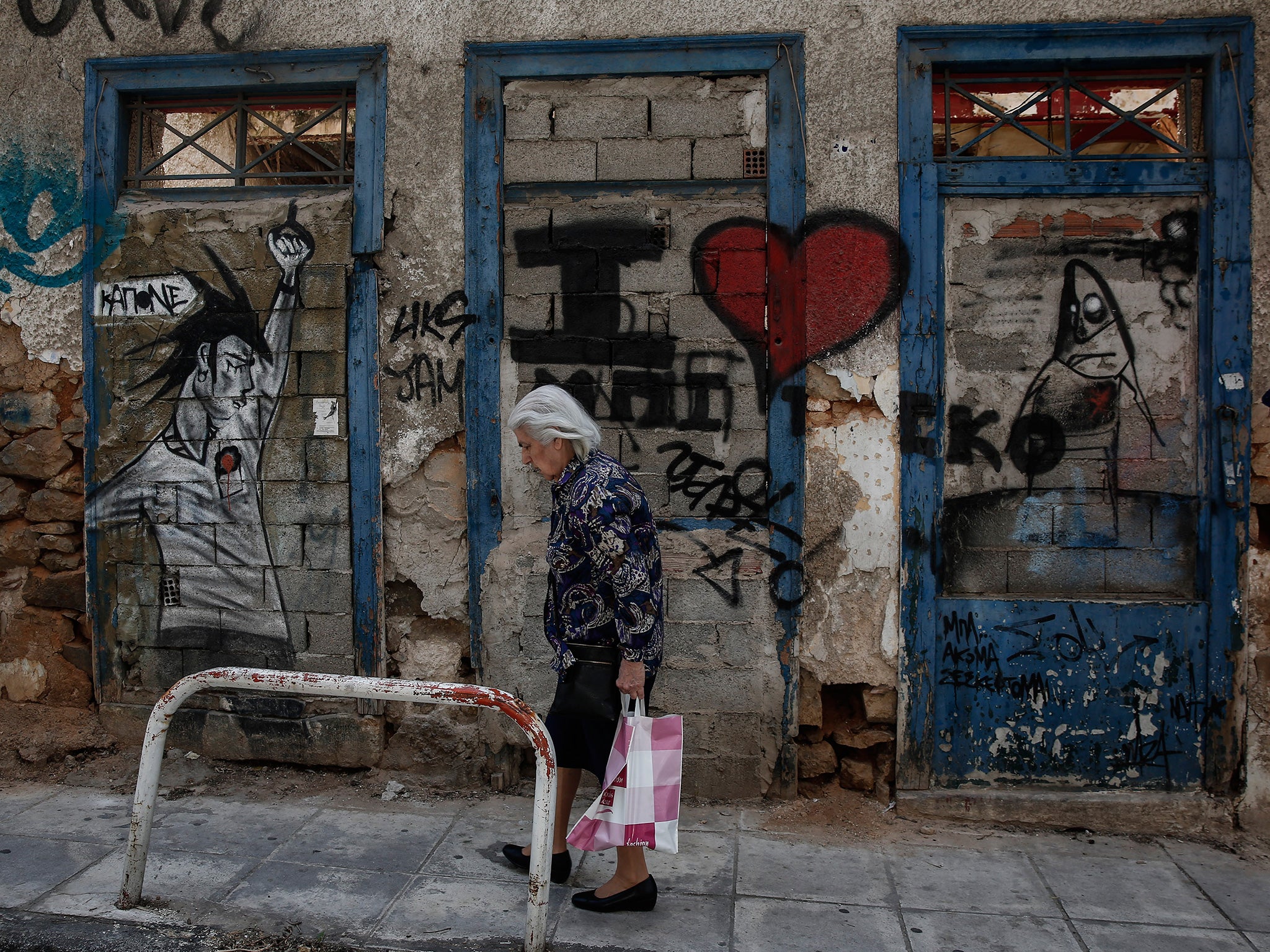 A woman walks past an abandoned house in Athens. The economy has slowed dramatically since January’s election