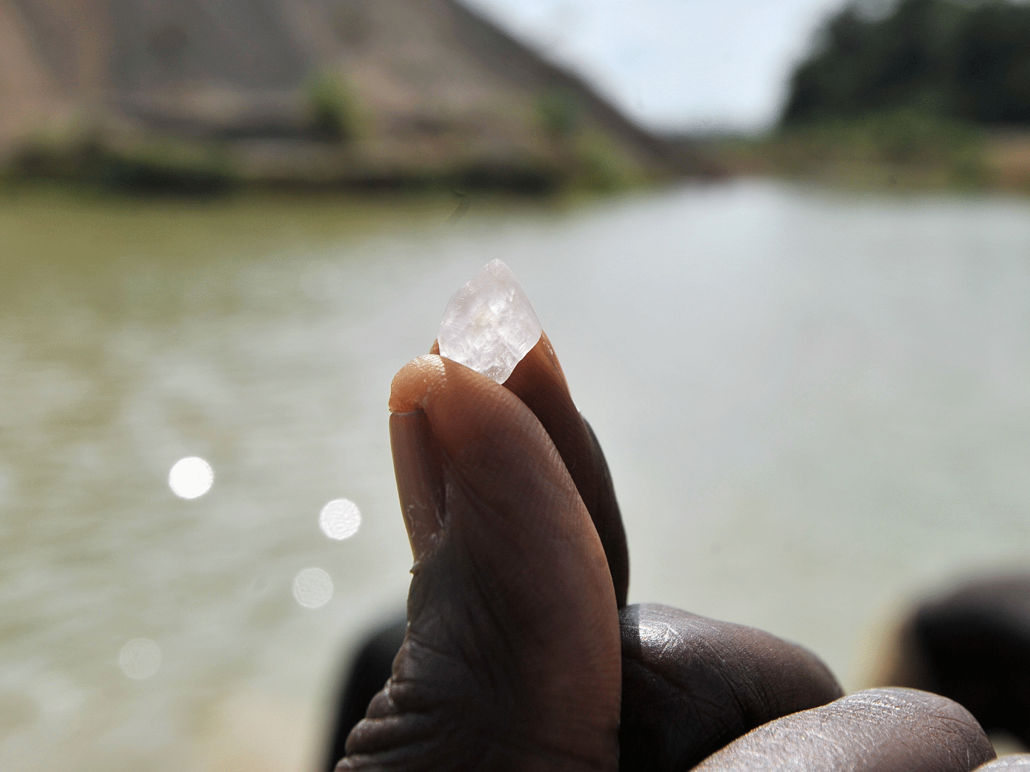 A diamond prospector holds up an uncut stone found in Sierra Leone, Africa's diamond capital