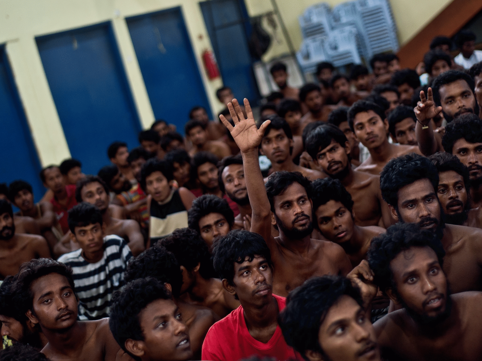An illegal Bangladeshi migrant raises his hand for clothes as they wait at the Police headquarters in Langkawi on May 11, 2015 after landing on Malaysian shores earlier in the day