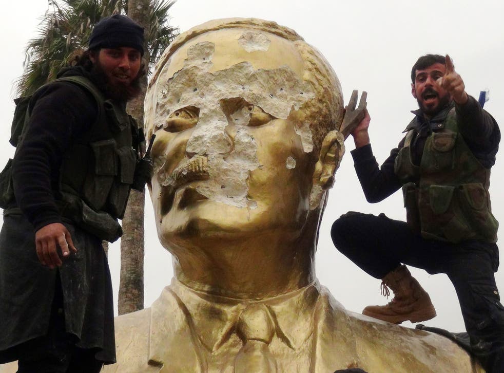 Fighters loyal to Jabhat al-Nusra and its allies smash a statue of the late Syrian leader Hafez al-Assad, father of current President Bashar al-Assad, in the Syrian city of Idlib