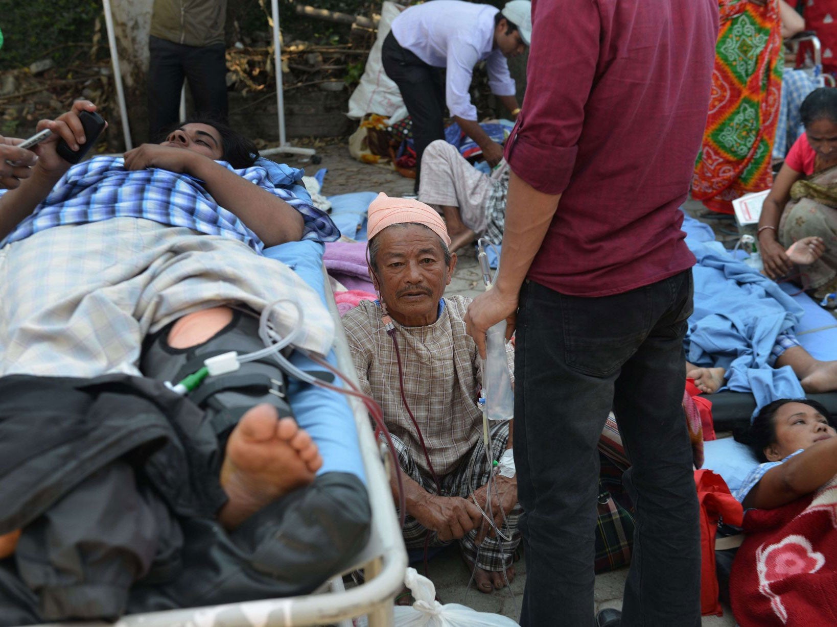 Nepalese patients lie on stretchers after being carried out of a hospital as a 7.3 magnitude earthquake hit Kathmandu on Tuesday