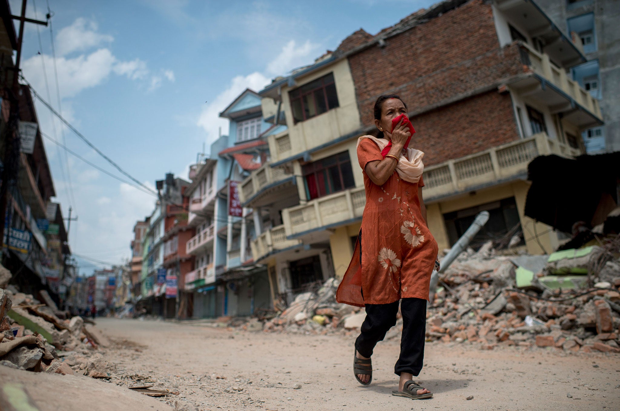 A woman walks past the rubble of destroyed buildings following a second major earthquake in Kathmandu, Nepal