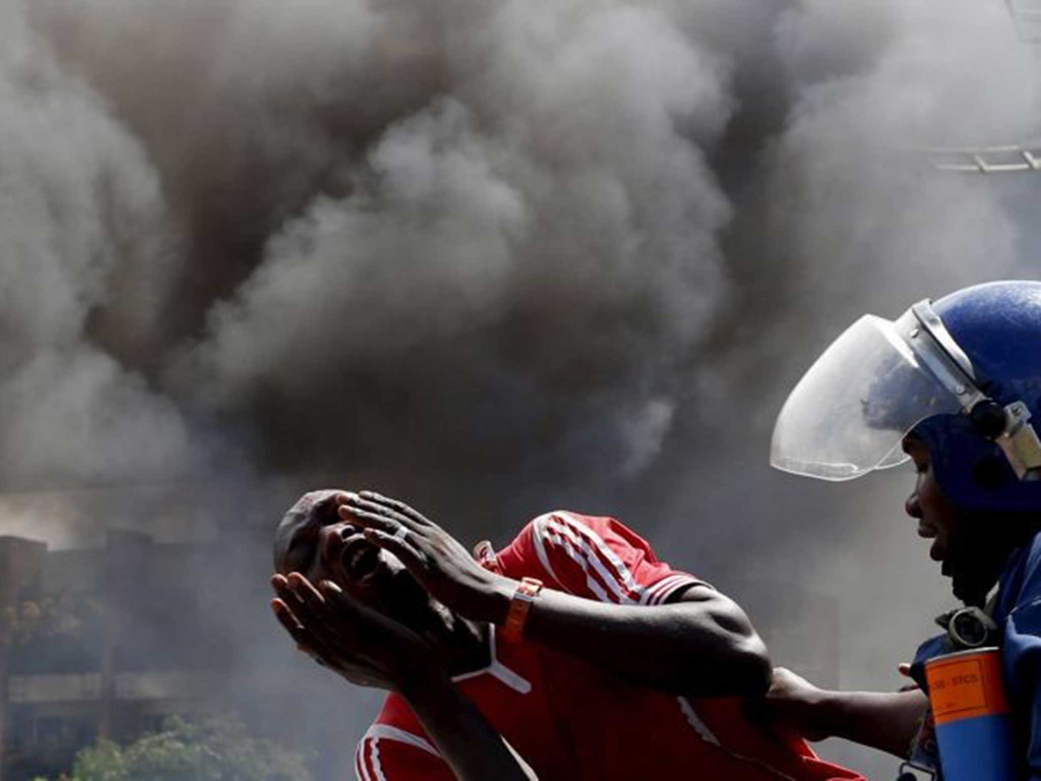 A man screams in the street as an Burundi police officer attempts to detain him