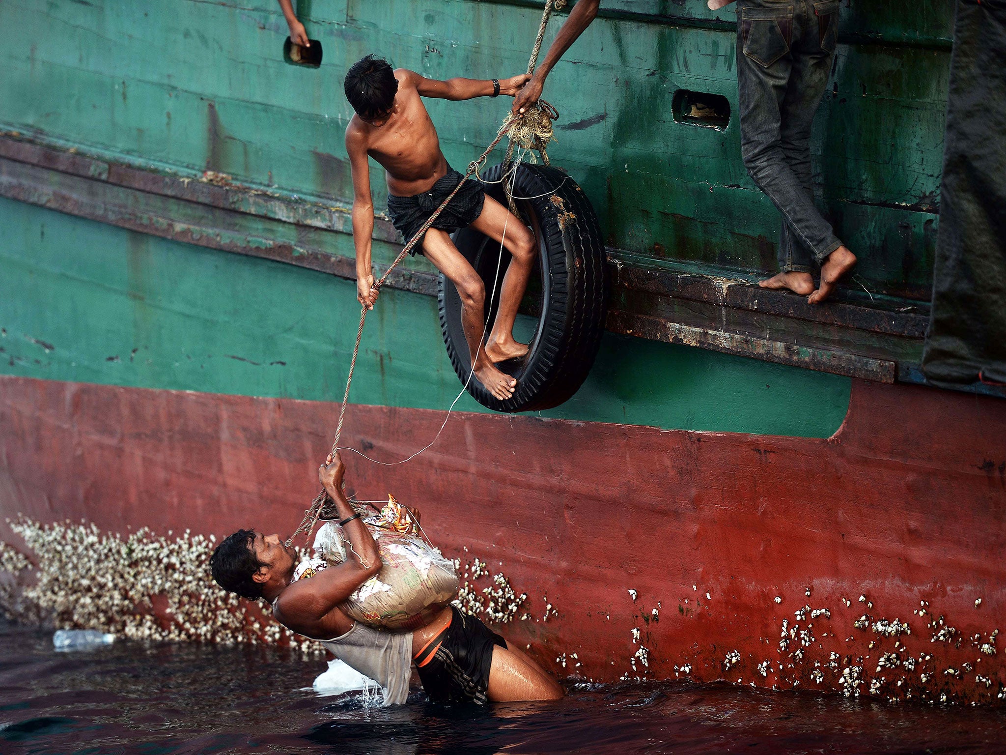 Rohingya migrants bring back food supplies dropped by a Thai army helicopter after jumping to collect them at sea from a boat drifting in Thai waters off the southern island of Koh Lipe in the Andaman sea
