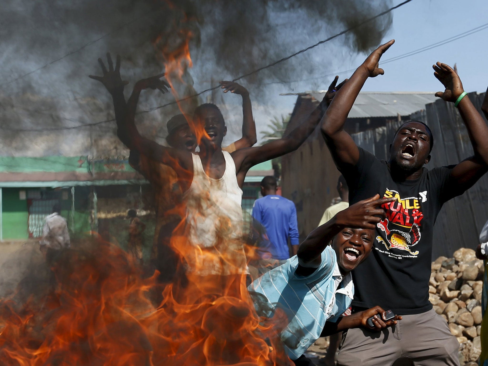 Protesters, who are opposed to President Pierre Nkurunziza’s decision to run for a third term, gesture in front of a burning barricade in Bujumbura, Burundi