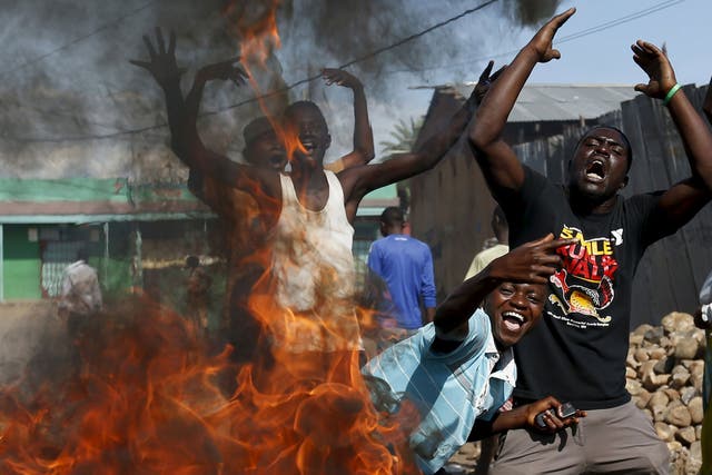 Protesters, who are opposed to President Pierre Nkurunziza’s decision to run for a third term, gesture in front of a burning barricade in Bujumbura, Burundi