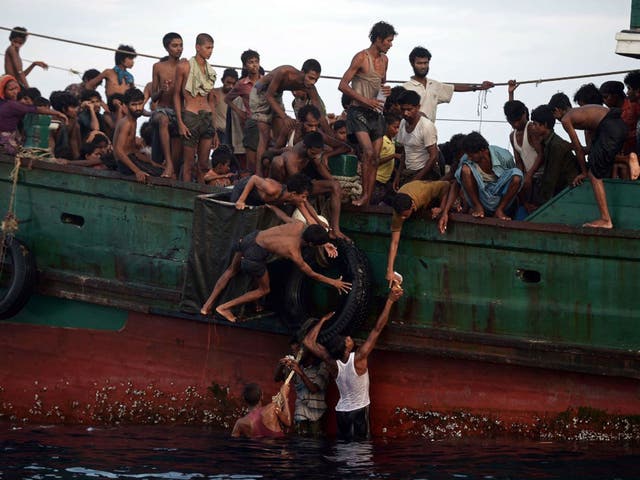 Rohingya migrants pass food supplies dropped by a Thai army helicopter to others aboard a boat drifting off the southern Thai island of Koh Lipe in the Andaman