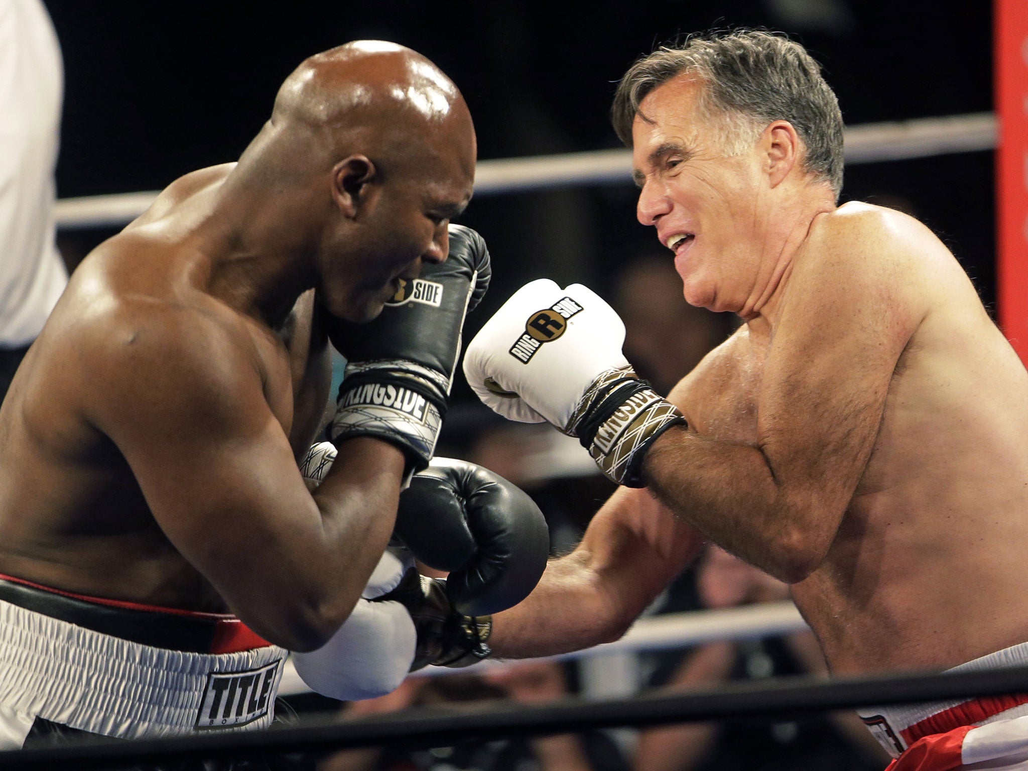 Former Republican presidential candidate Mitt Romney, right, throws punches with five-time heavyweight boxing champion Evander Holyfield