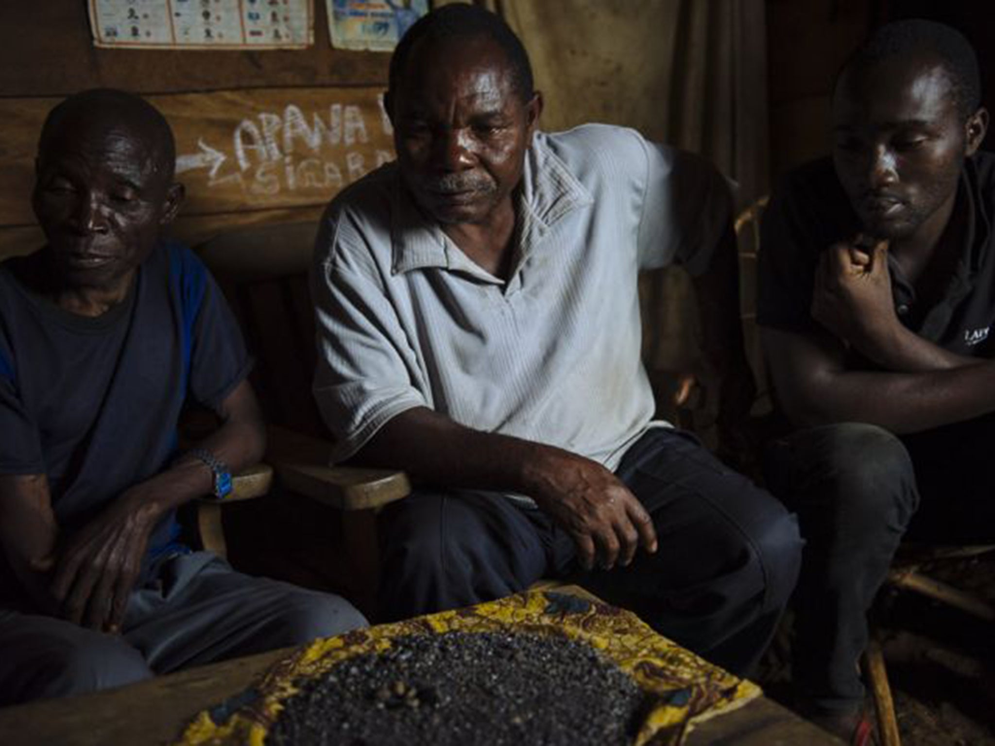 Donatien Watukarusu, centre, with his store of cassiterite – he was taxed in minerals by armed groups