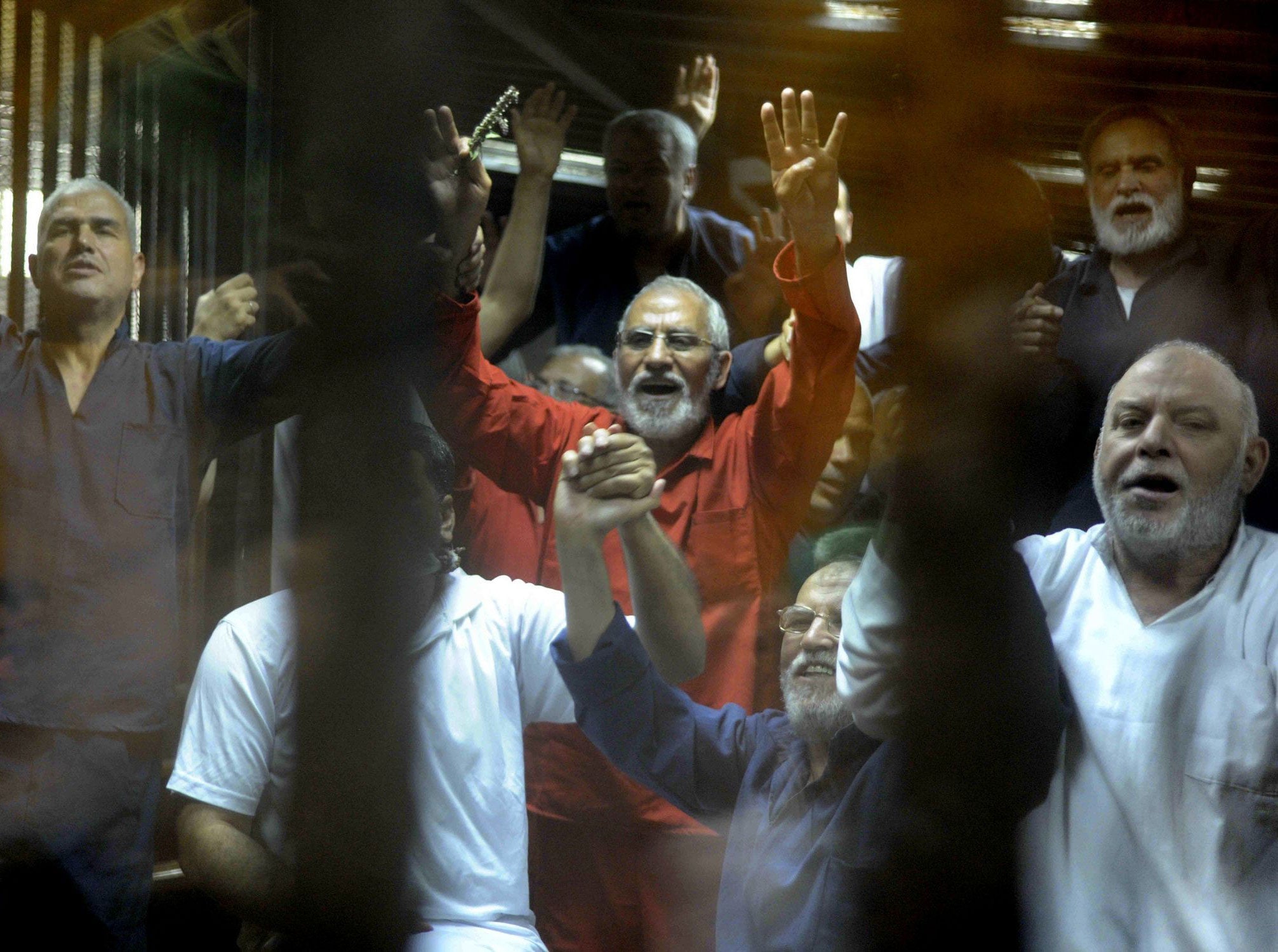 Egyptian defendants including the spiritual leader of the Muslim Brotherhood, Mohammed Badie, gesture as they are sentenced to death in a Cairo court