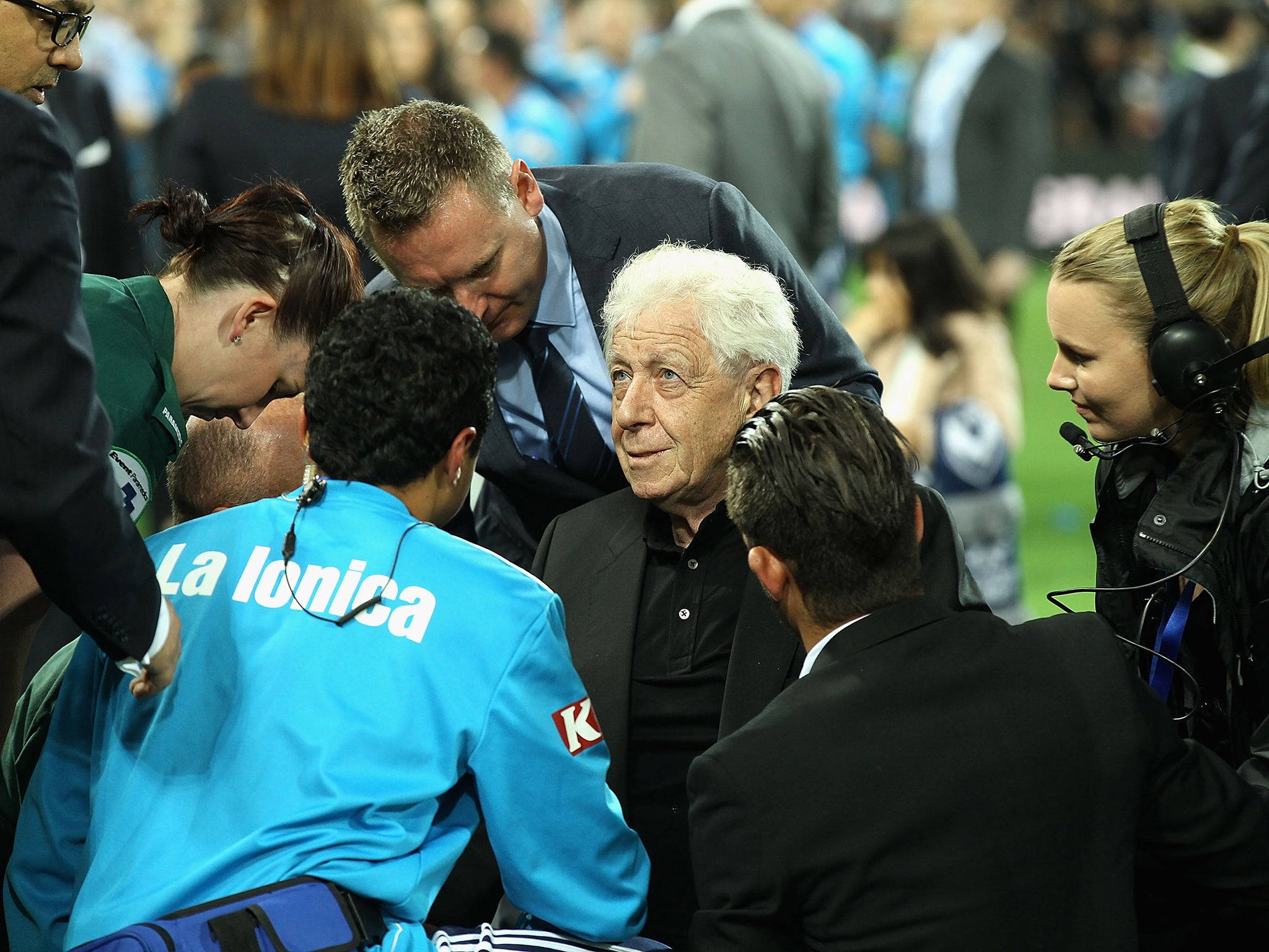 Frank Lowy is attended to by medics after falling from the stage as Melbourne won the Australia A-League trophy
