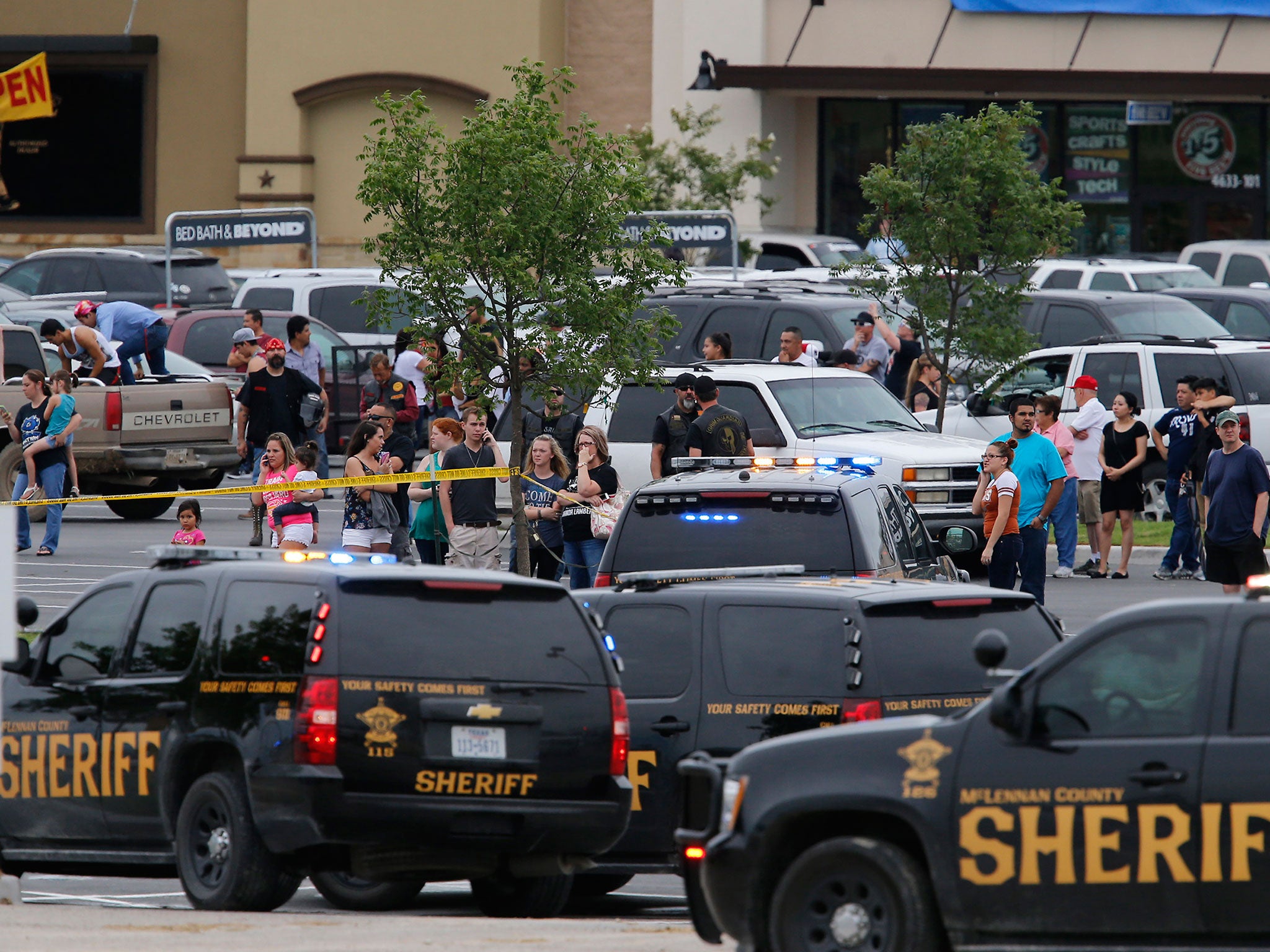 People at the Central Texas MarketPlace watch a crime scene near the parking lot of a Twin Peaks restaurant