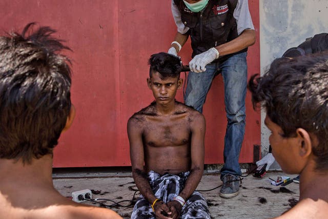 A volunteer cuts the hair of a Rohingya migrant at a temporary shelter in Kuala Langsa, Indonesia