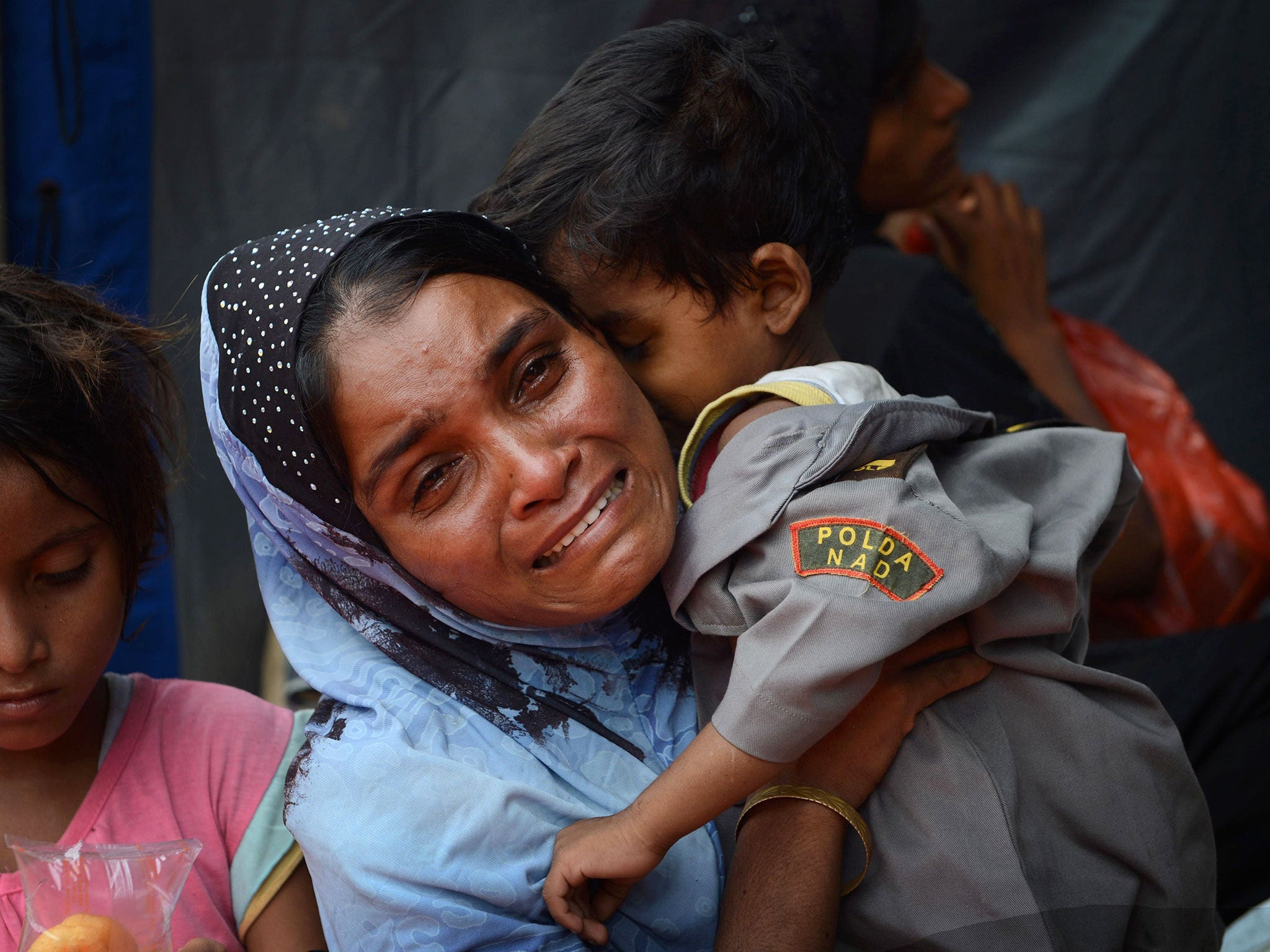 A migrant Rohingya woman from Myanmar breaks down while holding her son at the new confinement area in the fishing town of Kuala Langsa in Aceh province
