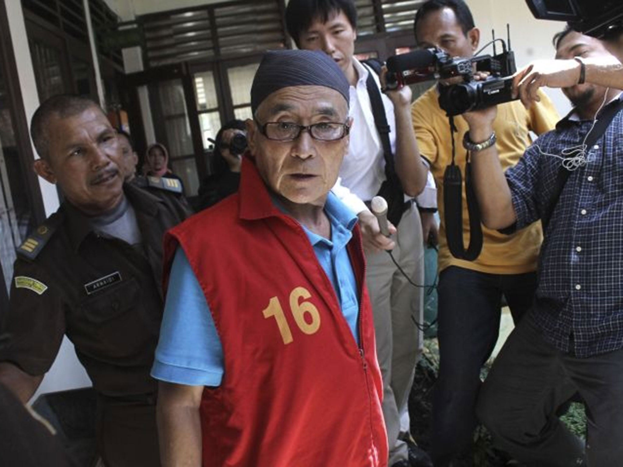 Japanese national Masaru Kawada, center, is mobbed by the media upon arrival for his sentencing hearing at the district court in Pariaman, West Sumatra, Indonesia
