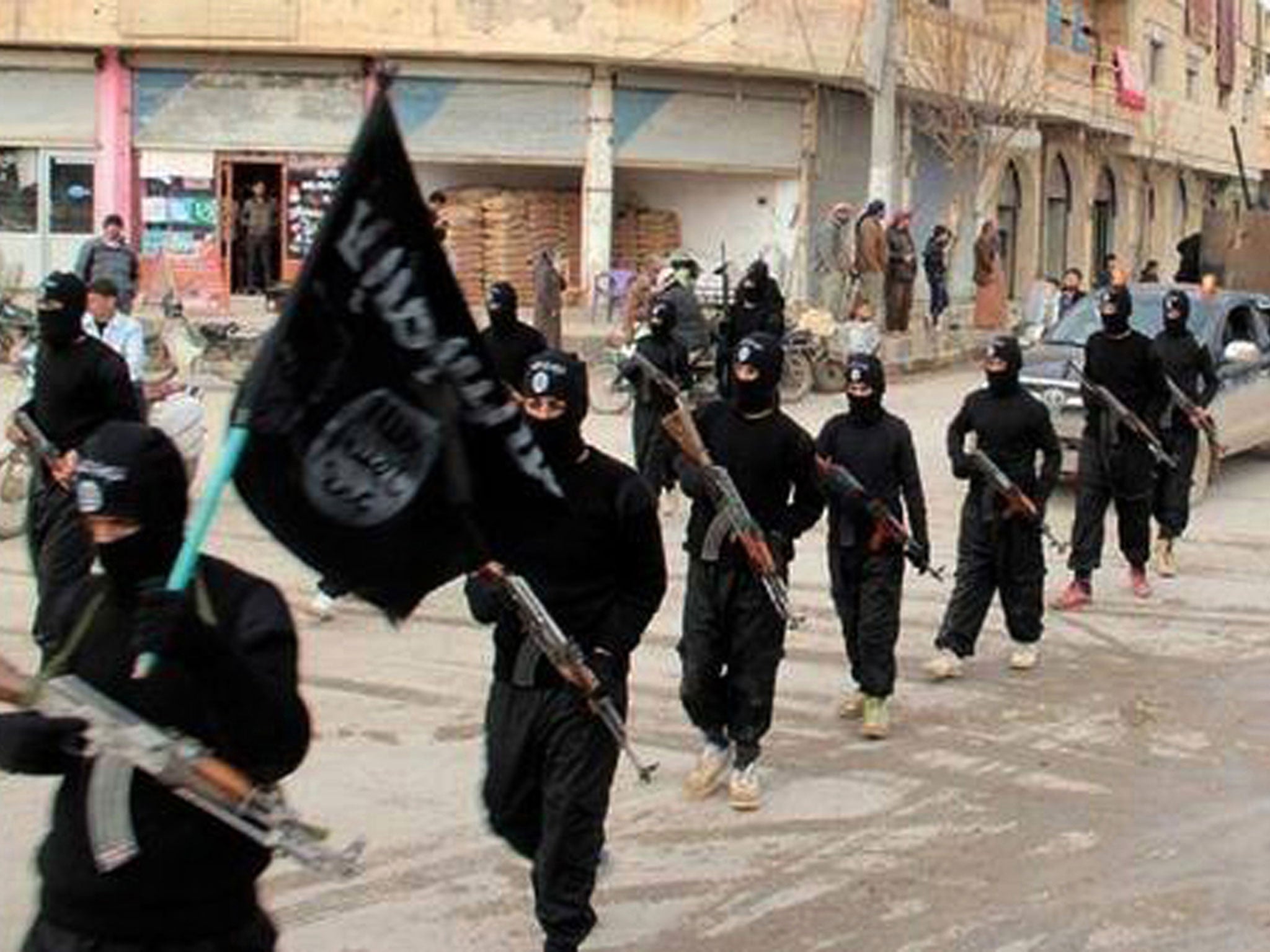Masked Isis fighters march through the Syrian city of Raqqa