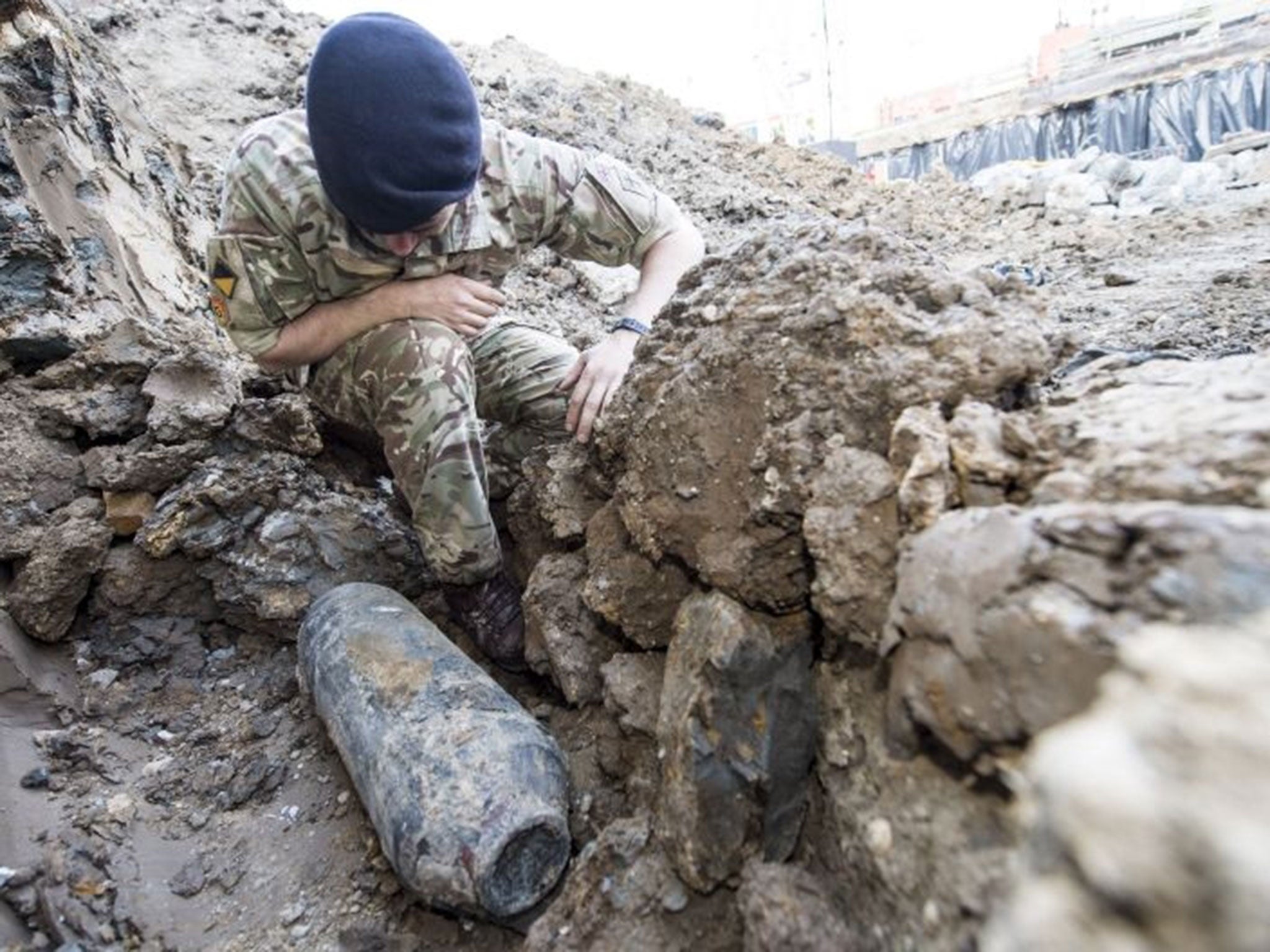 An army bomb disposal expert inspects an unexploded World War II bomb found in Wembley, north London, Thursday May 21, 2015. The 50-kilogram (110-pound) bomb was discovered by workers at a construction site near Wembley stadium. It is believed to have bee