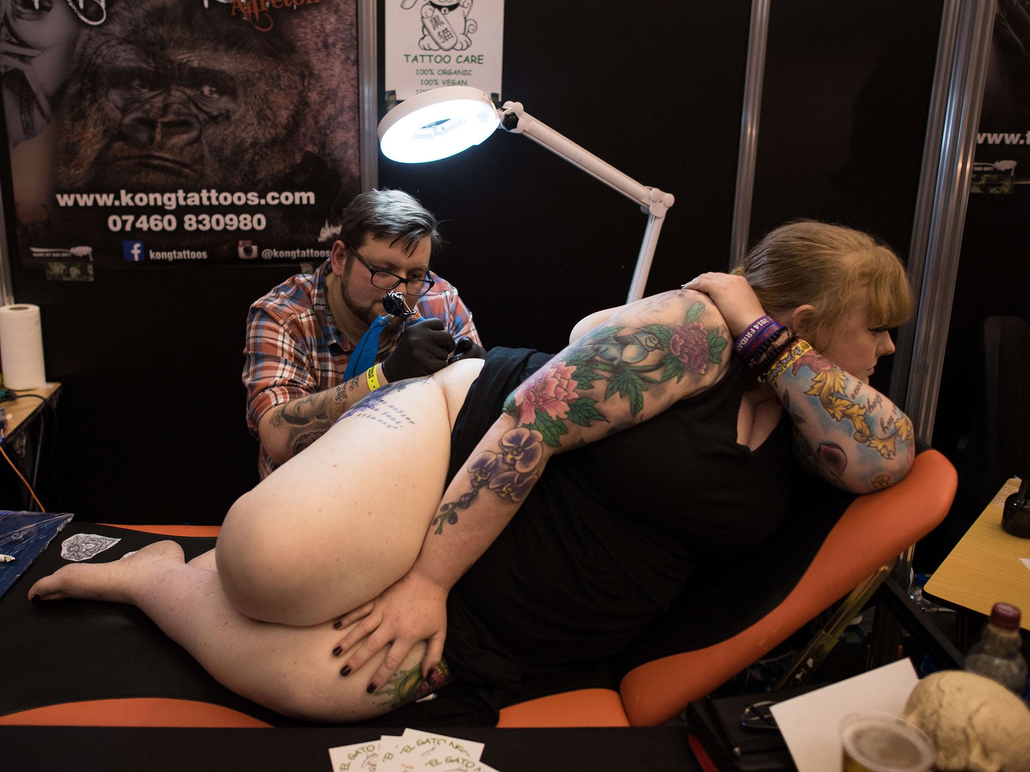 A customer has a piece of art tattooed onto her thigh at the Great British Tattoo Show