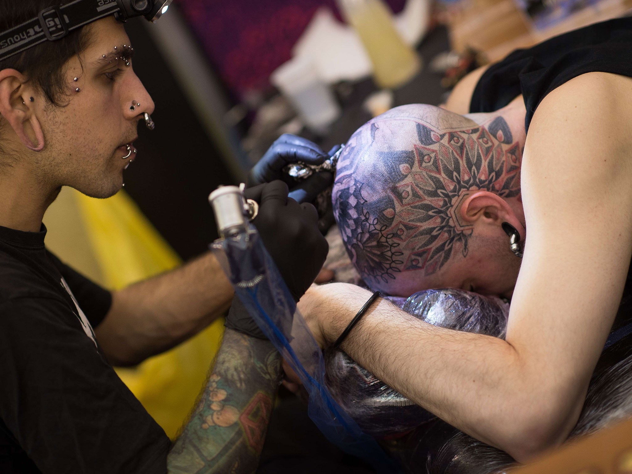 A customer has a piece of art tattooed onto his head at the Great British Tattoo Show