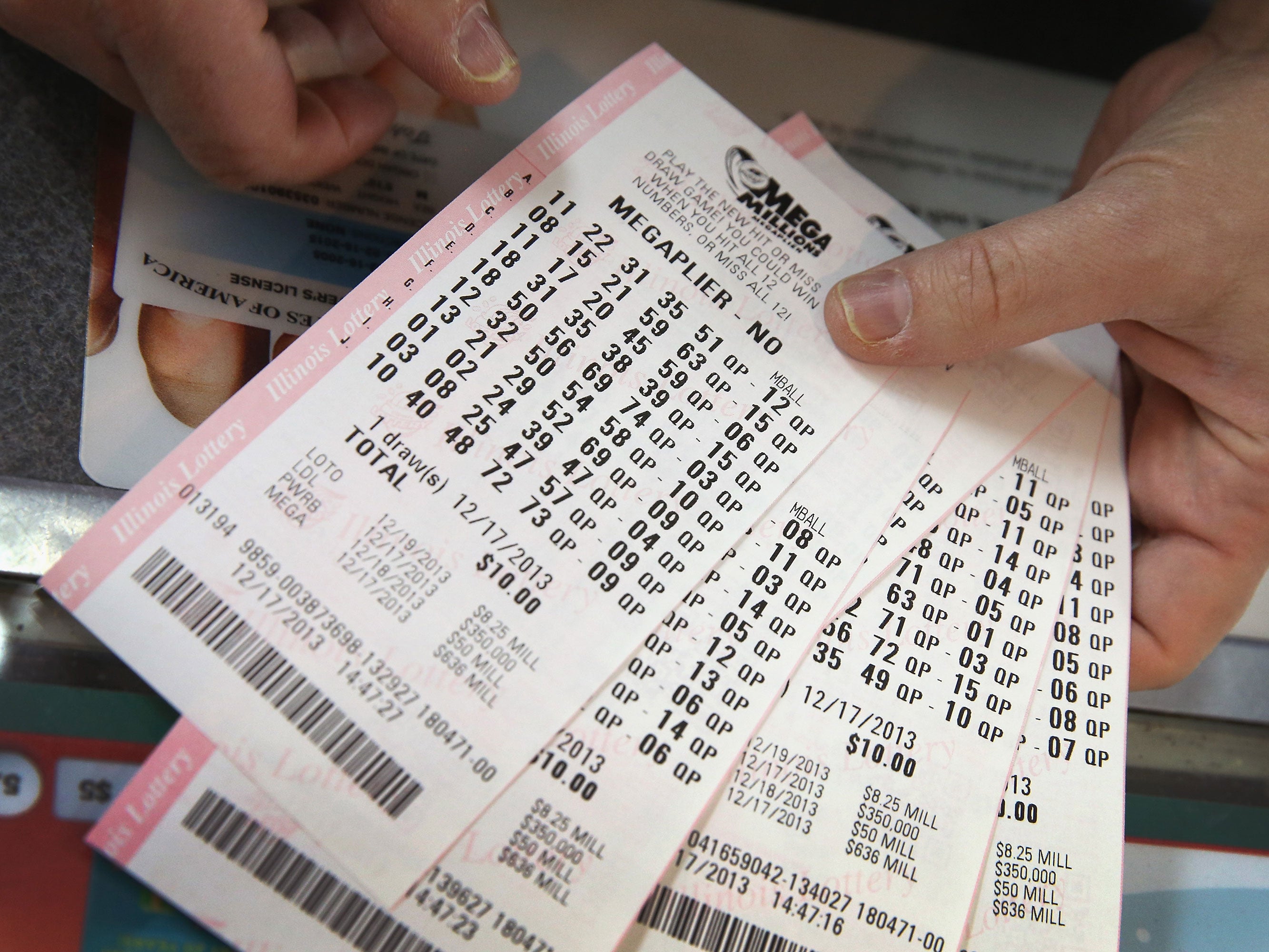 A customer holds a stack of Mega Millions lottery tickets which he purchased for his office pool at a convenience store on December 17, 2013 in Chicago, Illinois.