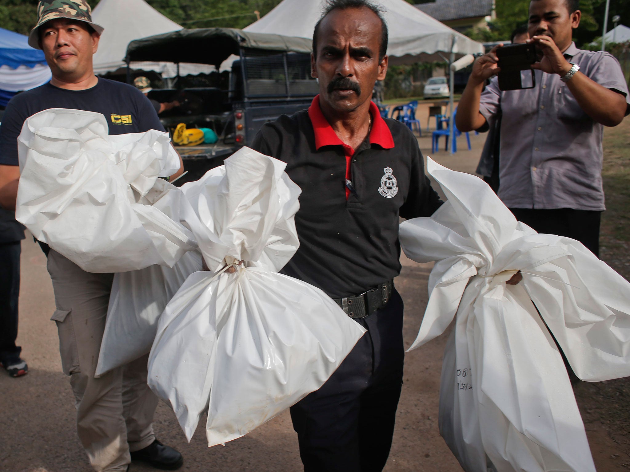 Malaysian police carry bags with human remains in Wang Kelian