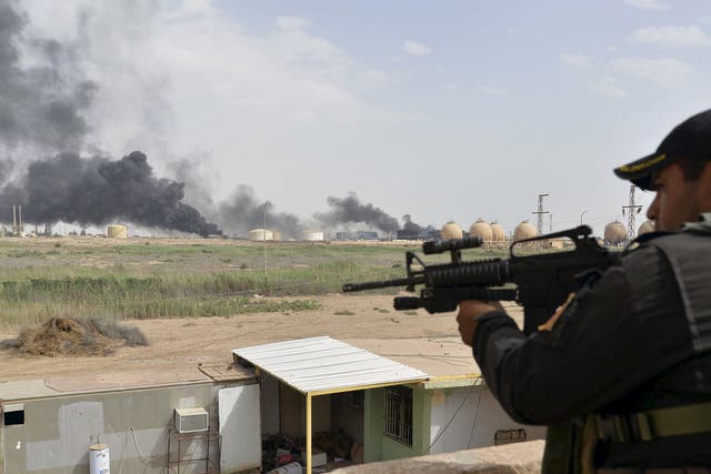 A member from the Iraqi security forces guards as smoke rises from Baiji oil refinery, north of Baghdad, Iraq May 26, 2015. Iraq's Shi'ite paramilitaries said on Tuesday they had taken charge of the campaign to drive Islamic State from the western provinc