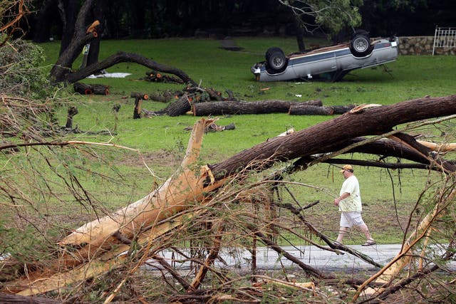 A man walks along the Blanco River where sweeping flood waters overturned vehicles and knocked down trees, in Wimberley 