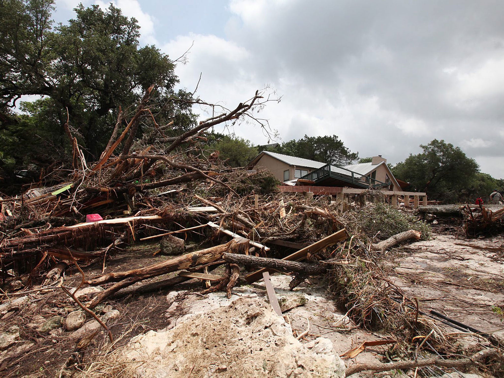 A flood damaged home and debris sits on the bank of the Blanco River in Wimberly