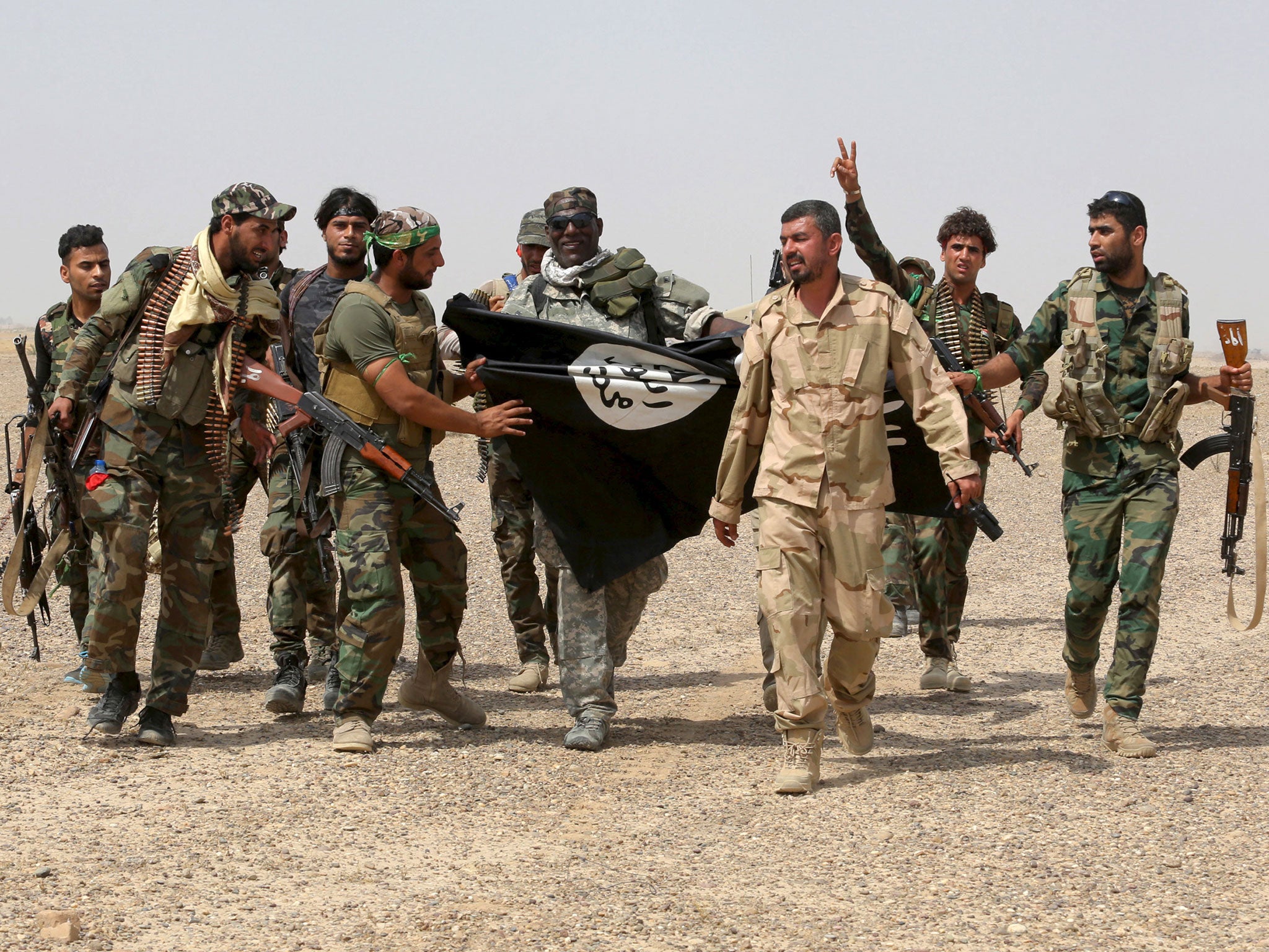 Iraq's Shi'ite paramilitaries and members of Iraqi security forces hold an Islamist State flag which they pulled down in Nibai