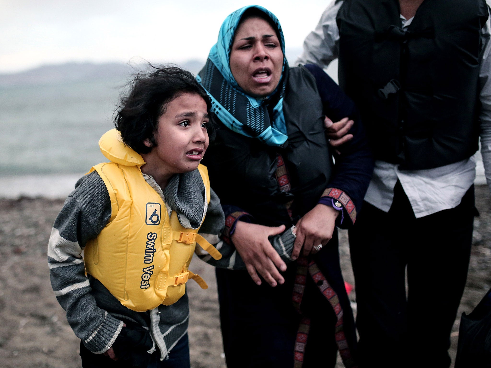 An Afghan migrant girl holds the hand of a woman as they arrive on a beach on the Greek island of Kos