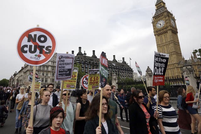 Protesters march with banners during an anti-austerity protest after the Queen's Speech was delivered to Parliament in London, Wednesday, May 27, 2015