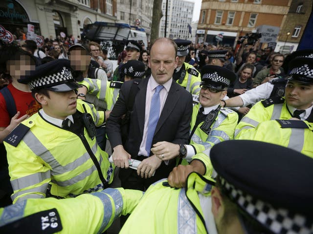 Douglas Carswell is escorted by police after being surrounded by protesters during an anti-austerity protest following the Queen's Speech