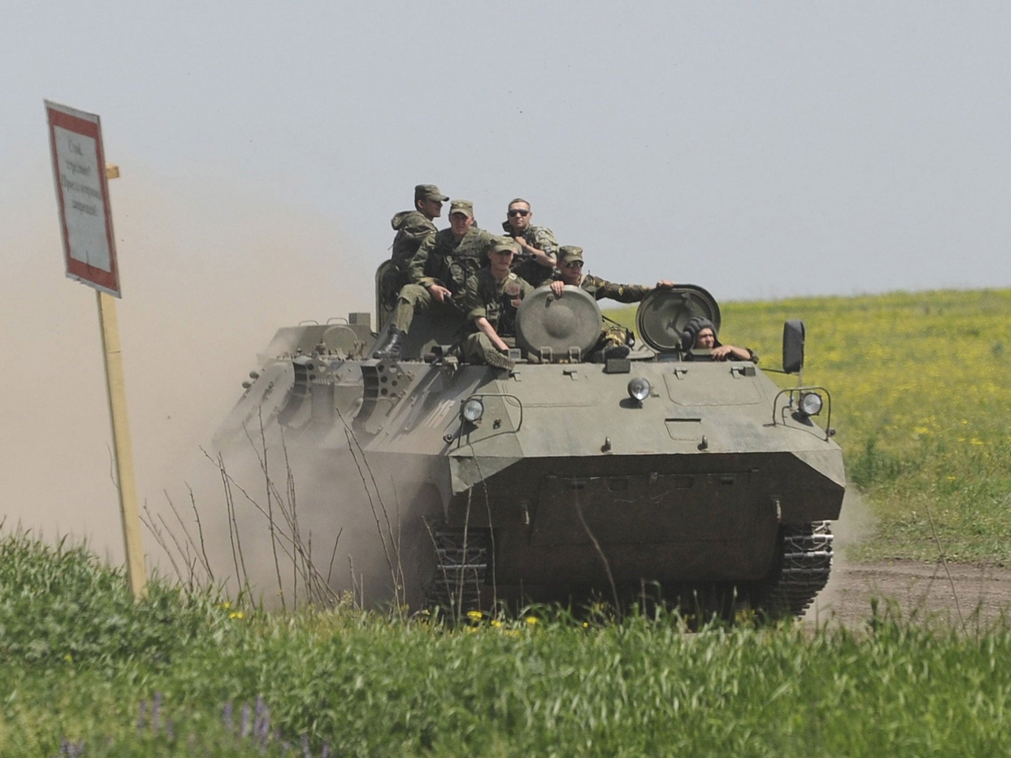 Men wearing military uniforms ride atop an armoured personnel carrier (APC) during exercises at the Kuzminsky military training ground near the Russian-Ukrainian border in Rostov region