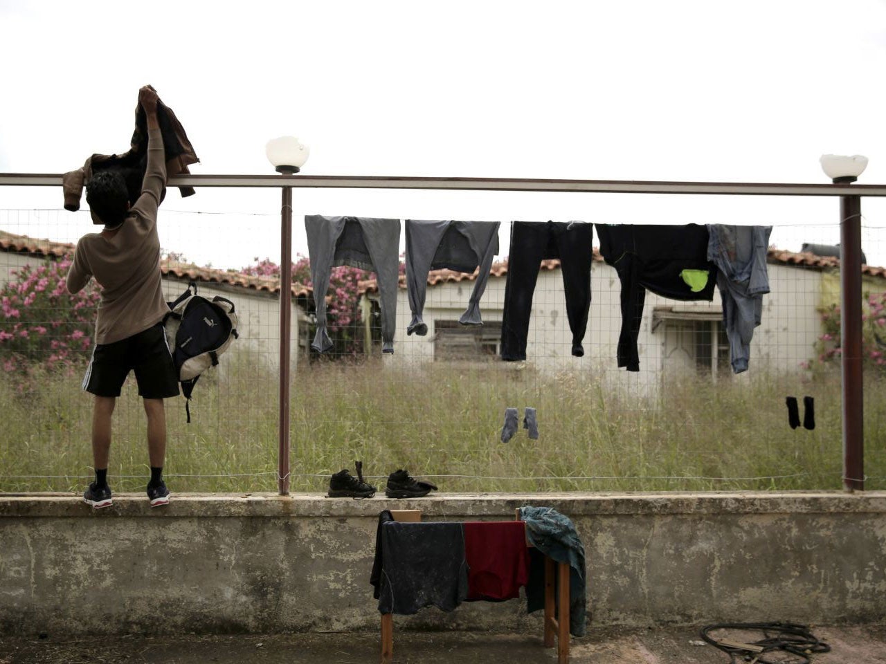 A migrant hangs his clothes on a fence of an abandoned hotel