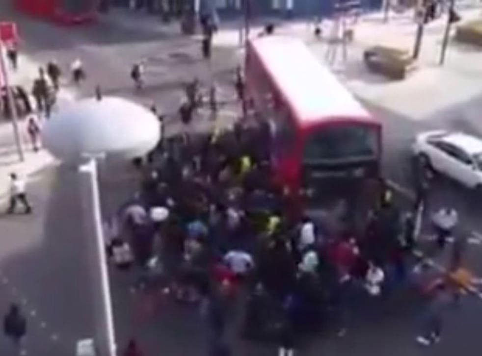 Bystanders attempt to lift the bus off the man